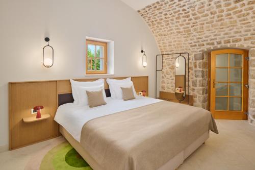 a bedroom with a large bed and a brick wall at Palace Natali in Dubrovnik