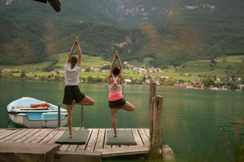 two women doing yoga on a dock on a lake at Leuchtenburg am See in Caldaro