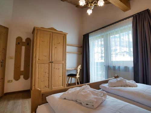 a bedroom with two beds and a window with a chair at Hotel Monte44 in Selva di Val Gardena