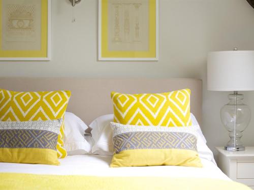 a bedroom with a bed with yellow and white pillows at The Sparsholt Barn in Wantage