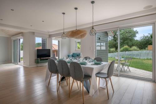 une salle à manger avec une table et des chaises blanches dans l'établissement Maison avec piscine pour 8 adultes - 2 enfants, à Pornic