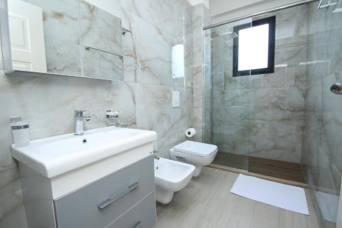 een badkamer met een wastafel, een toilet en een douche bij Hotel Roalb in Vlorë