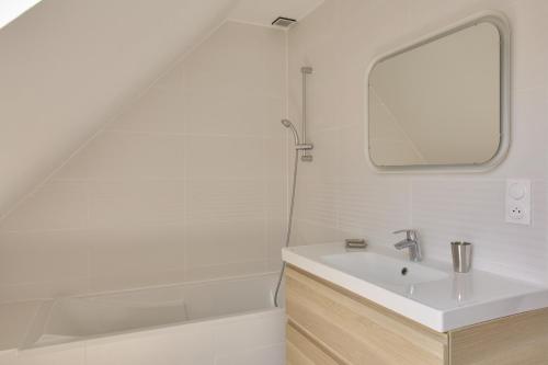 ein Badezimmer mit einem Waschbecken, einem Spiegel und einer Badewanne in der Unterkunft Calme, detente et decouvertes en famille in Plobannalec-Lesconil