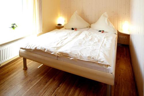 a bed with white sheets and pillows in a room at Maikäfer in Bliesdorf