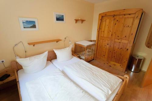 BliesdorfにあるKornblumeの白いベッドと木製のドアが備わるベッドルーム1室が備わります。