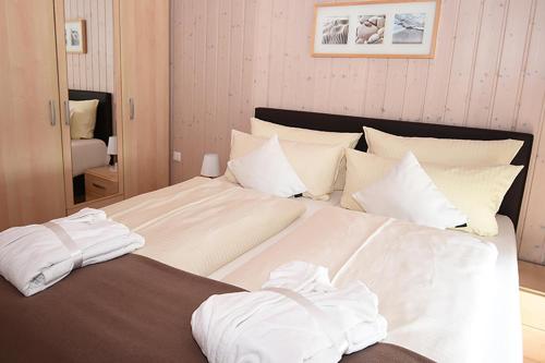 1 dormitorio con 1 cama grande con sábanas y almohadas blancas en Lachmöwe, en Bliesdorf