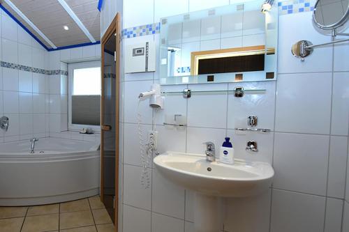 y baño con lavabo, bañera y espejo. en Lachmöwe, en Bliesdorf