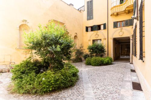 un patio de un edificio con un árbol y arbustos en Rosa Luxury Apartment en Verona