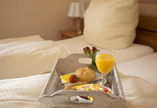 a tray of food and a glass of orange juice on a bed at Klabautermann in Grömitz