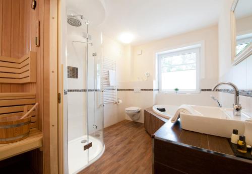 ein Badezimmer mit einem Waschbecken, einer Badewanne und einer Dusche in der Unterkunft Ankerplatz in Grömitz
