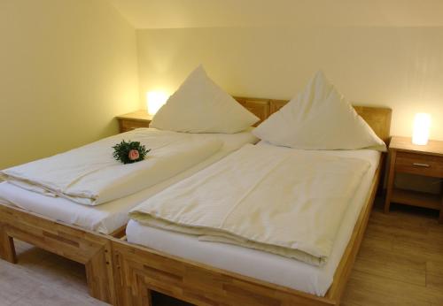 2 Betten mit weißer Bettwäsche und einer Blume darauf in der Unterkunft Dana in Grömitz