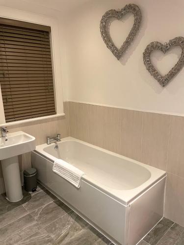 a bathroom with a tub and two hearts on the wall at The Place - Lytham in Lytham St Annes