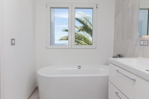 德尼亞的住宿－Villa Siesta，白色的浴室设有白色浴缸和窗户。
