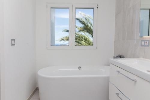 a white bathroom with a white tub and a window at Villa Siesta in Denia