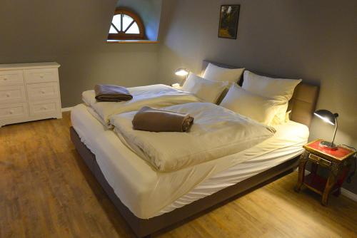 ein großes Bett mit weißer Bettwäsche und einem braunen Beutel darauf in der Unterkunft Lieblingsplatz in Grömitz
