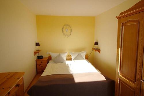 BliesdorfにあるZaunkönigのベッドルーム1室(白いシーツと木製キャビネット付)
