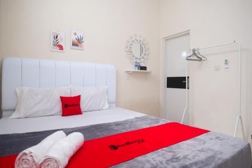 a bedroom with a white bed with red pillows at RedDoorz Syariah near Universitas Mercu Buana Kampus 2 Yogyakarta in Yogyakarta