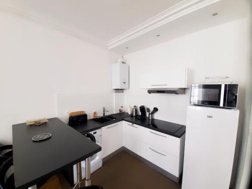 une cuisine avec des armoires blanches et un comptoir noir dans l'établissement Le Perrot - 38m2 - 1 chambre, à La Rochelle