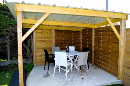 a wooden pavilion with a table and chairs at Le Chalet à Hub - extérieur, proche de la plage in Asnelles