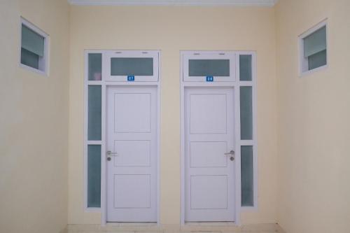 two white doors in a white room with windows at RedDoorz Syariah near Universitas Mercu Buana Kampus 2 Yogyakarta in Yogyakarta