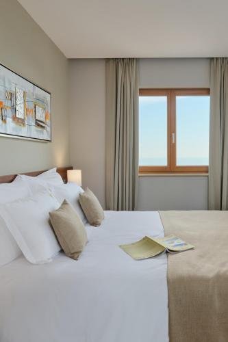 a white bedroom with a large white bed with pillows at Palace Natali in Dubrovnik