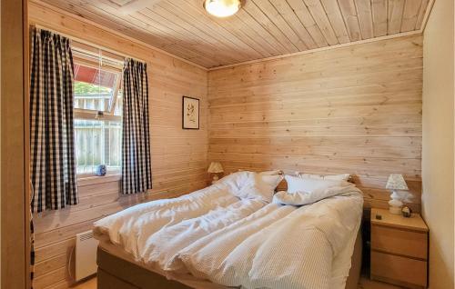 a bed in a room with a wooden wall at Beautiful Home In Jrpeland With Wifi And 2 Bedrooms in Jørpeland