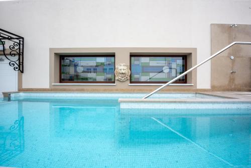 a large swimming pool in a building with windows at Hotel Casa Palacio María Luisa in Jerez de la Frontera
