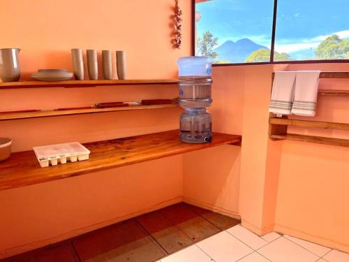 uma cozinha com uma prateleira com uma garrafa de água em Casa Rosa em Panajachel