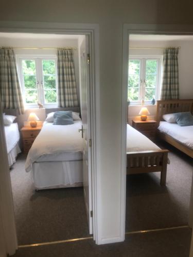 a bedroom with two beds and two windows at Liming Lodge - Lakeside Home in the Cotswolds in South Cerney