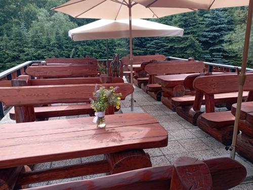 a row of wooden benches with umbrellas and flowers on them at Wellness Hotel Koliba in Komorní Lhotka
