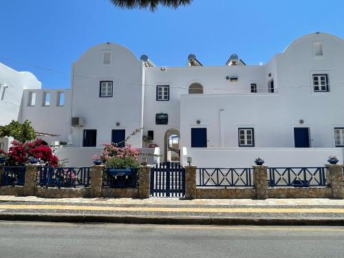 a white building with a fence in front of it at Leonidas Apartments in Kamari