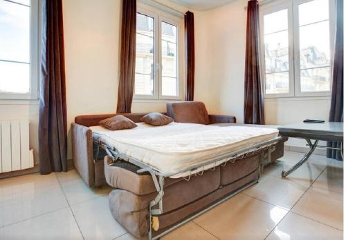 Cette chambre comprend un grand lit et des fenêtres. dans l'établissement Apartment Notre Dame Bright, à Paris