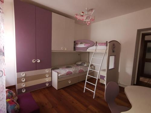 a bedroom with a bunk bed and a ladder at Casa Phoenix Appartamento piano terra immerso nel verde a pochi minuti dalla ciclabile in Pieve di Cadore