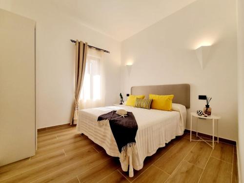 um quarto com uma grande cama branca com almofadas amarelas em STAZZO SAN TEODORO IL GINEPRO em San Teodoro