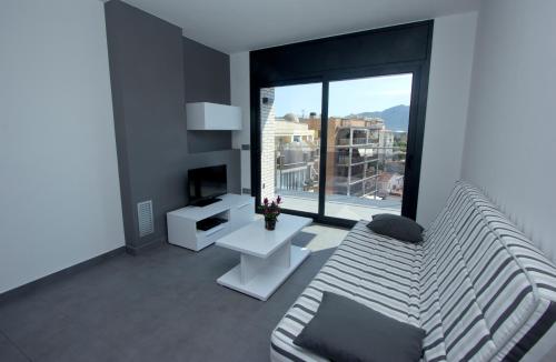 a living room with a couch and a large window at InmoSantos Apartaments Nuria in Roses