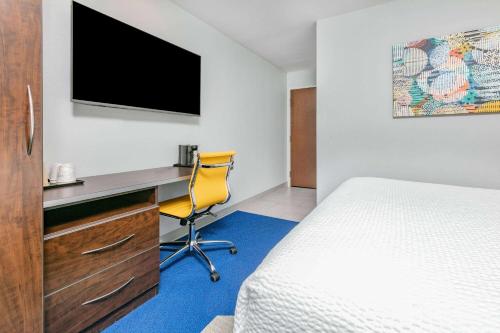 a hotel room with a bed and a desk with a television at Microtel Inn & Suites by Wyndham Austin Airport in Austin