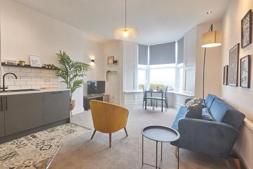 a living room with a blue couch and a kitchen at 5 Roker Terrace - Seaview Apartments in Sunderland