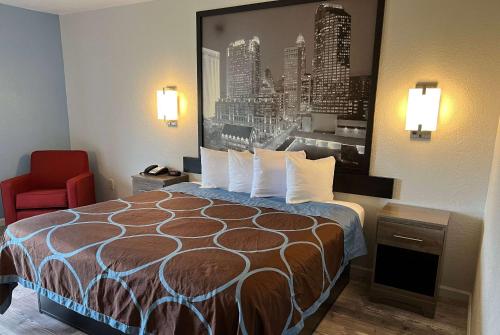 a hotel room with a bed and a red chair at Super 8 by Wyndham Clemmons - Bermuda Run - Winston-Salem I-40 in Clemmons