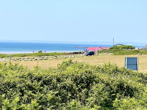 a beach with bushes and the ocean in the background at Lush Porthcawl Large Spacious 3 bedroom Apt, Prime Location in Porthcawl