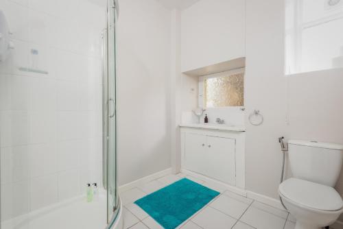 uma casa de banho branca com um chuveiro e um WC. em Murray Place - Central 2 Bed Apt em St. Andrews