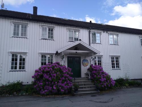 um edifício branco com flores roxas em frente em Grong Gård Guesthouse em Grong