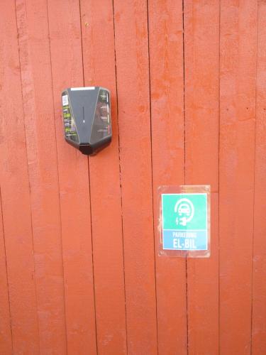 a parking meter on a wooden wall with a blue sign at Grong Gård Guesthouse in Grong