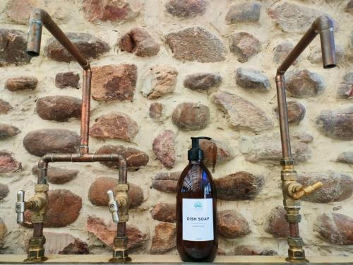 - un mur en pierre avec deux robinets et une bouteille de vin dans l'établissement Gaia Double or Twin Bell Tent, à Swellendam