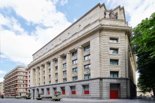 Un grand bâtiment blanc avec une statue en haut dans l'établissement Radisson Collection Bilbao, à Bilbao