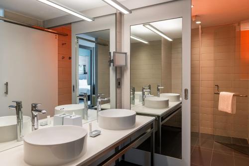 a bathroom with four sinks and two mirrors at Aloft Palm Jumeirah in Dubai