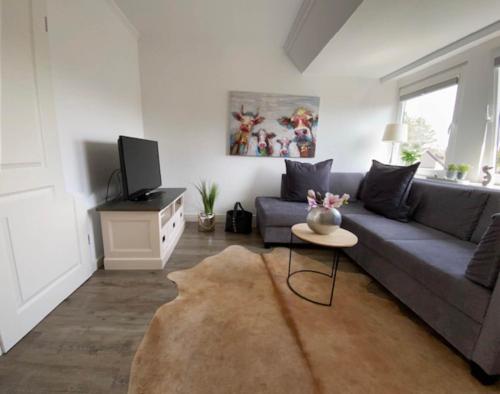 ein Wohnzimmer mit einem grauen Sofa und einem Tisch in der Unterkunft Anja in Westerland