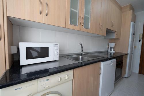 a kitchen with a microwave and a sink at Pension O Camiño Milladoiro in Amés