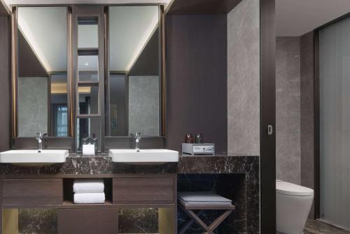 La salle de bains est pourvue de 2 lavabos et d'un grand miroir. dans l'établissement Ramada by Wyndham Bayannur, à Bayannuur