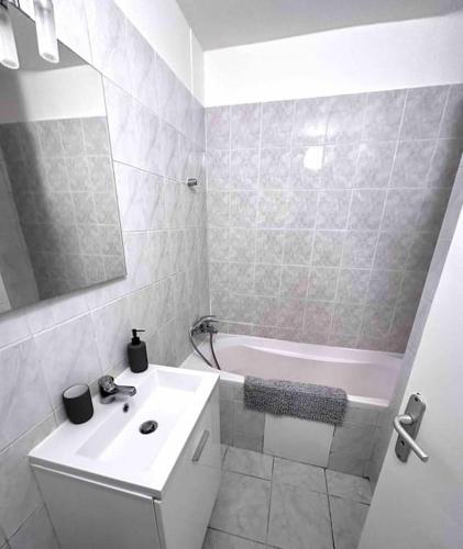 une salle de bain blanche avec un lavabo et une baignoire dans l'établissement T3 entier rénové avec place de parking, à Montpellier