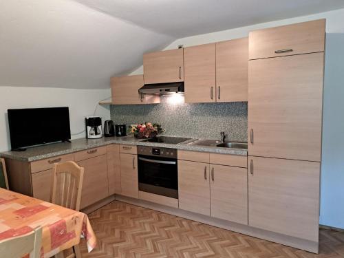 eine Küche mit Holzschränken und einem Esstisch in der Unterkunft Apartment Maiklerhof - MHO787 by Interhome in Ramsau im Zillertal